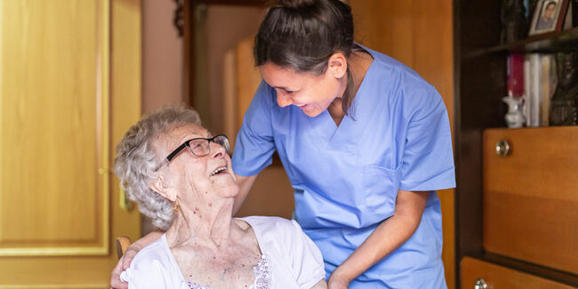 Alte Dame lacht häusliche Pflegerin an