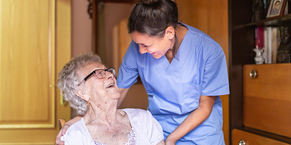 Alte Dame lacht häusliche Pflegerin an